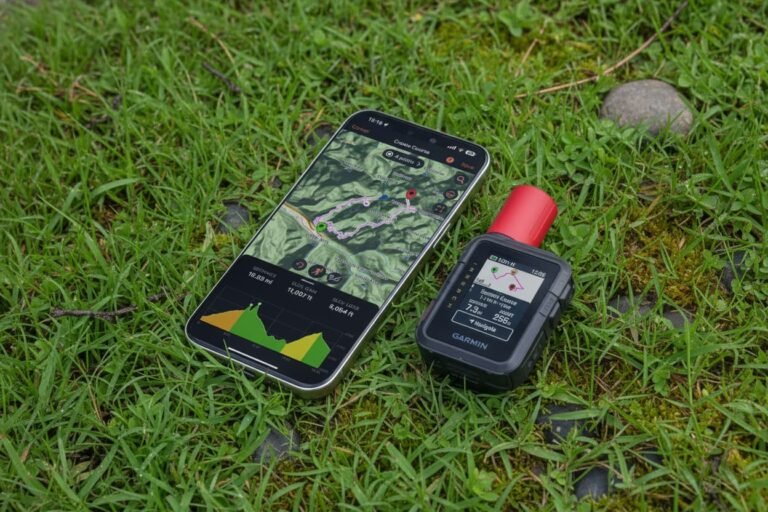 Garmin inReach Mini 2 clipped to a hiking backpack strap in the mountains.